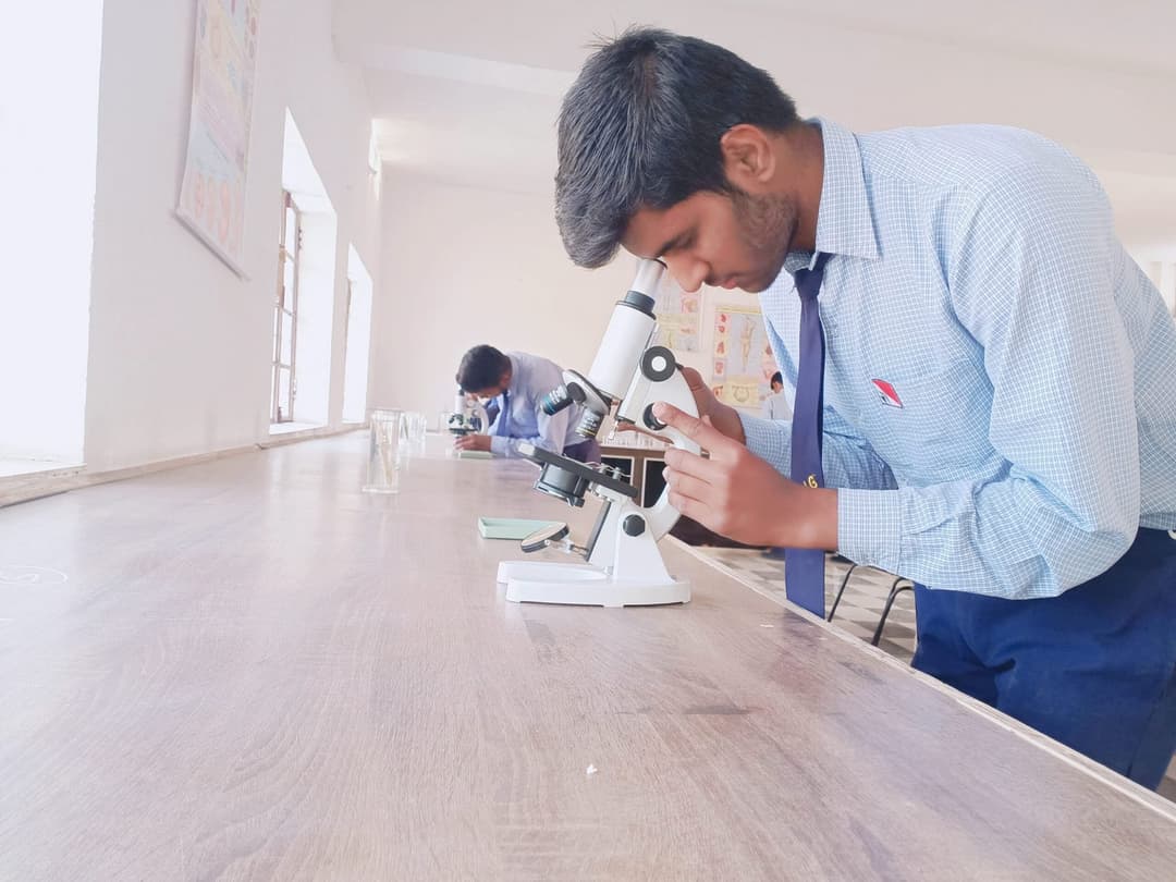 A student studying through a microscope in the biology lab